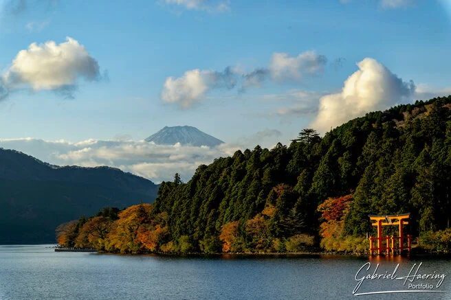 Red torii gate of Hakone Shrine on Lake Ashi with Mount Fuji and autumn forest in the background