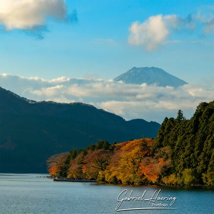 Mount Fuji appearing above Lake Ashi during a boat crossing under a clearing sky